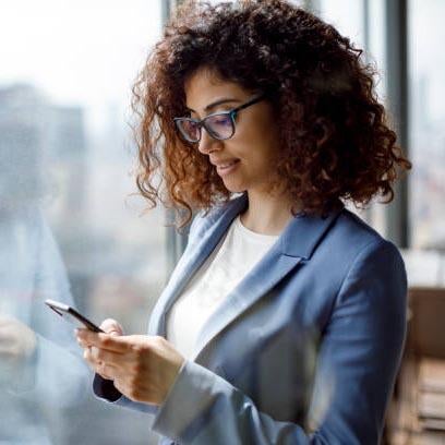 A professional-looking woman checks her cell phone.