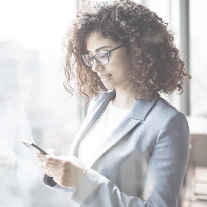 Woman in professional attire works on her smart phone.