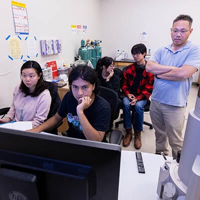 Several people stand around a computer screen.