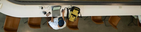 A man works on a computer on a long bench.