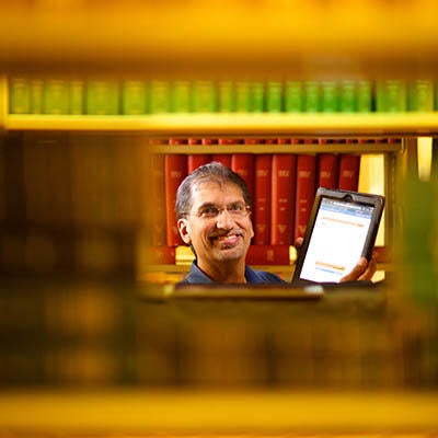 A man stands holding a tablet.