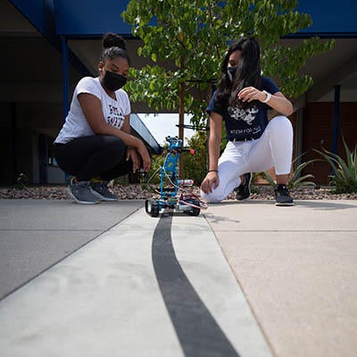 Two young technicians work on a robot together.