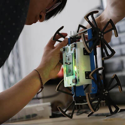 A technician works on a small robot.