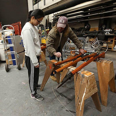 A student and a technician stand over a product they're working on together.