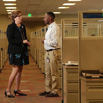 Two business people talk in an empty office.